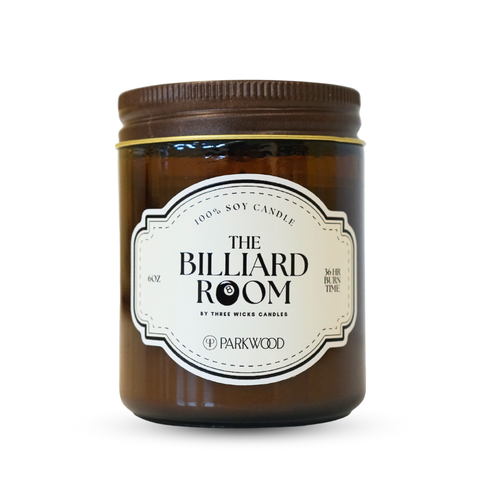 Brown glass candle jar with a label  that says "The Billiard Room" with an 8 ball as one of the o's