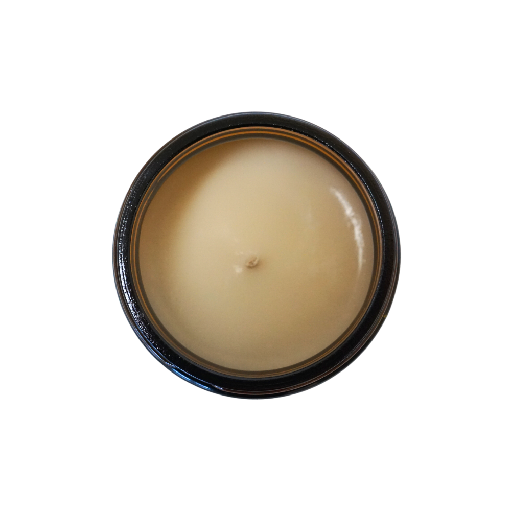 overhead shot of a light brown candle in a brown candle jar