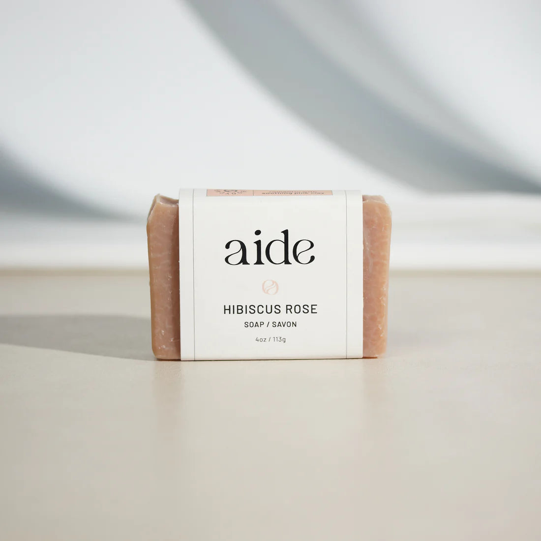 light pink/beige bar of soap with a white band label that has black text