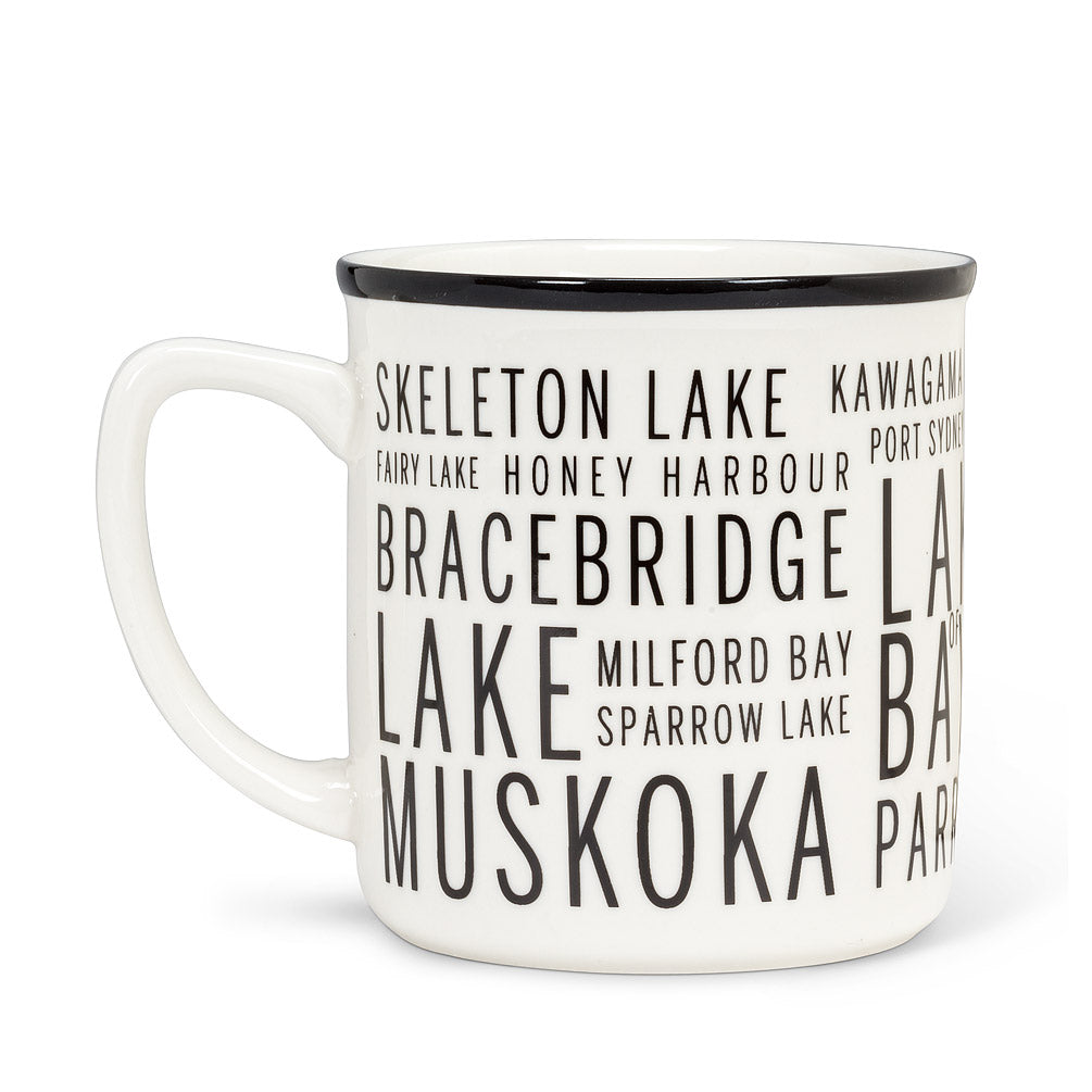 white mug and with a black rim, with different sied text of different areas in cottage country