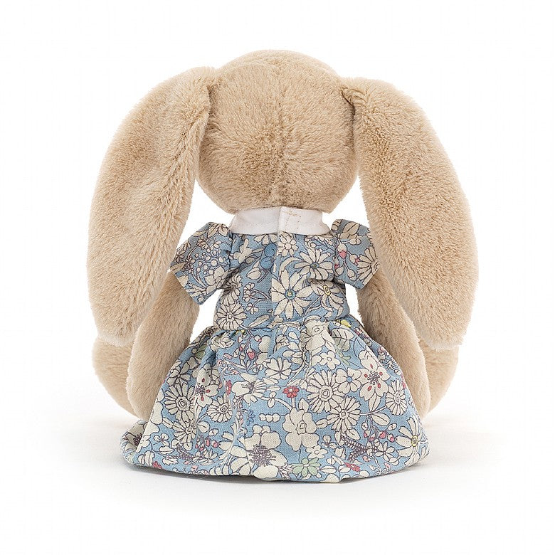 rear view of a light beige plush fluffy bunny rabbit wearing a light blue floral city