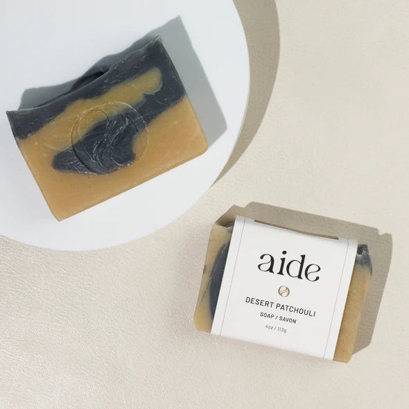 two bars of dark blue and light brown soap on a white plate,