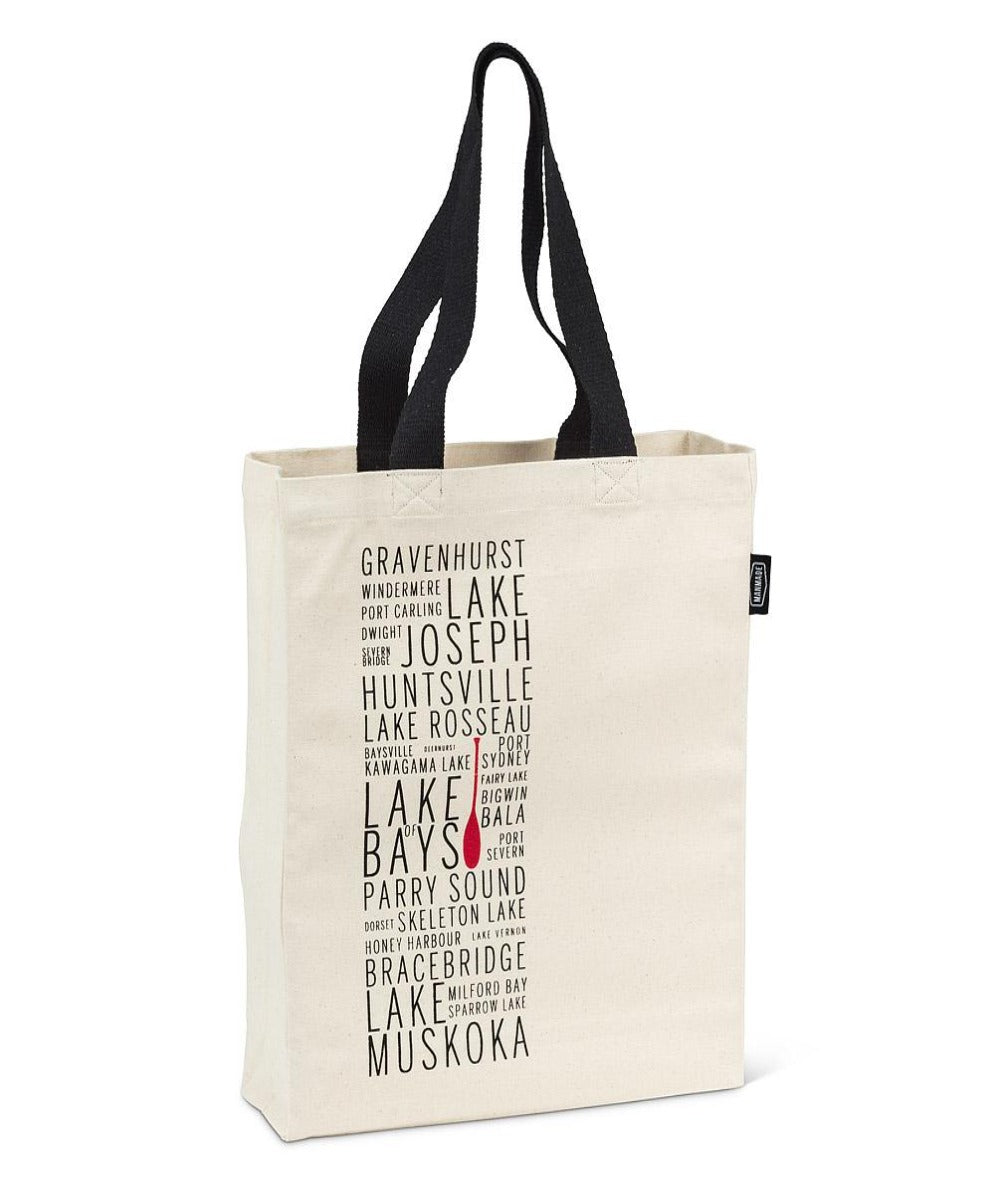 white tote bag with black handles with text of various ontario lakes with a red paddle in the middle 