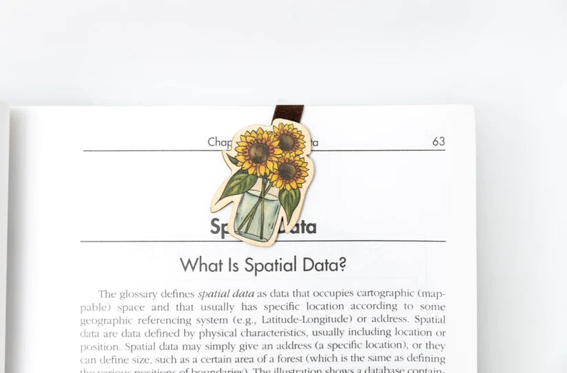 wooden sunflowers in a vase clipped onto a page of a book