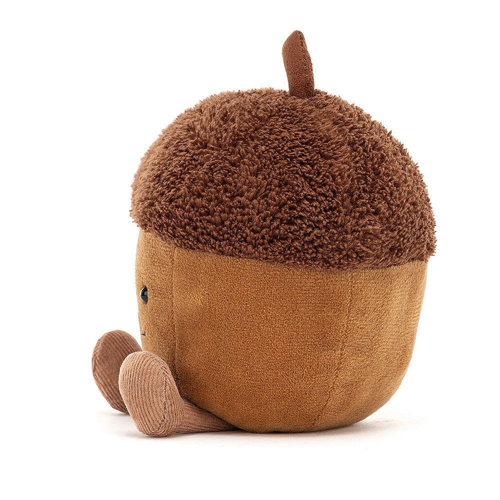 Side view of a smiling plush light brown acorn with light brown legs, and a dark brown top