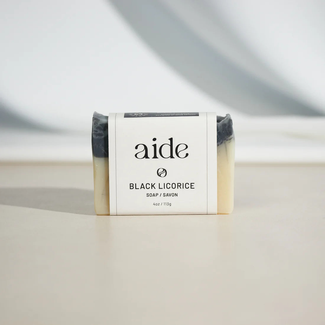 Black/off white bar of soap sporting a white band with black text 