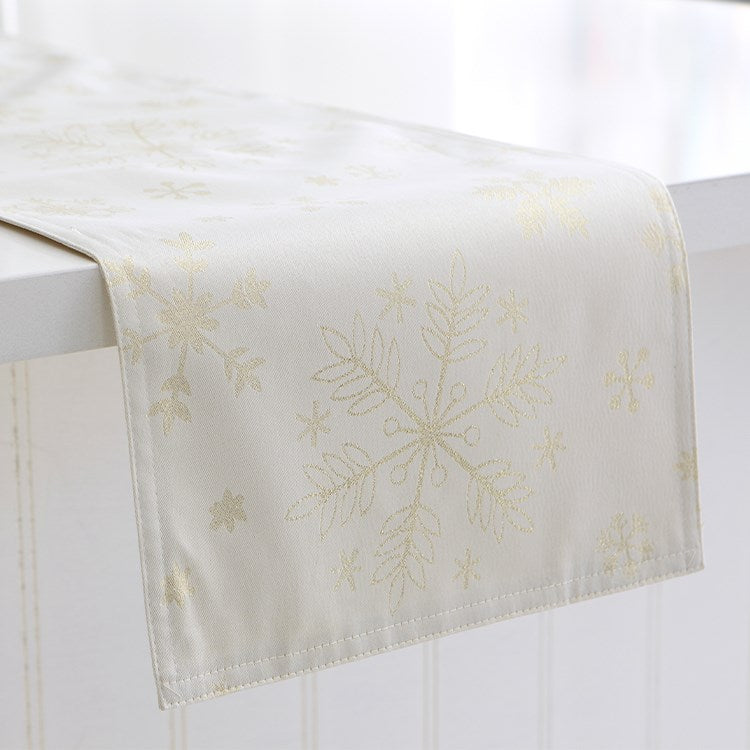 white table runner with a gold snowflake design hanging on a white countertop