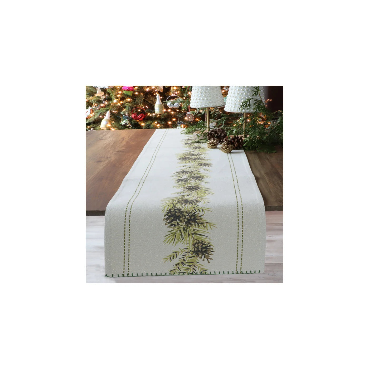 white table runner with a vintage linework border and mistletoe running up the middle while resting on a table with christmas decorations behind it 