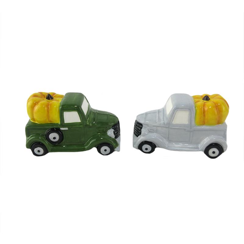 Two salt and pepper shakers in the shaoe of green and grey trucks carrying yellow pumpkins