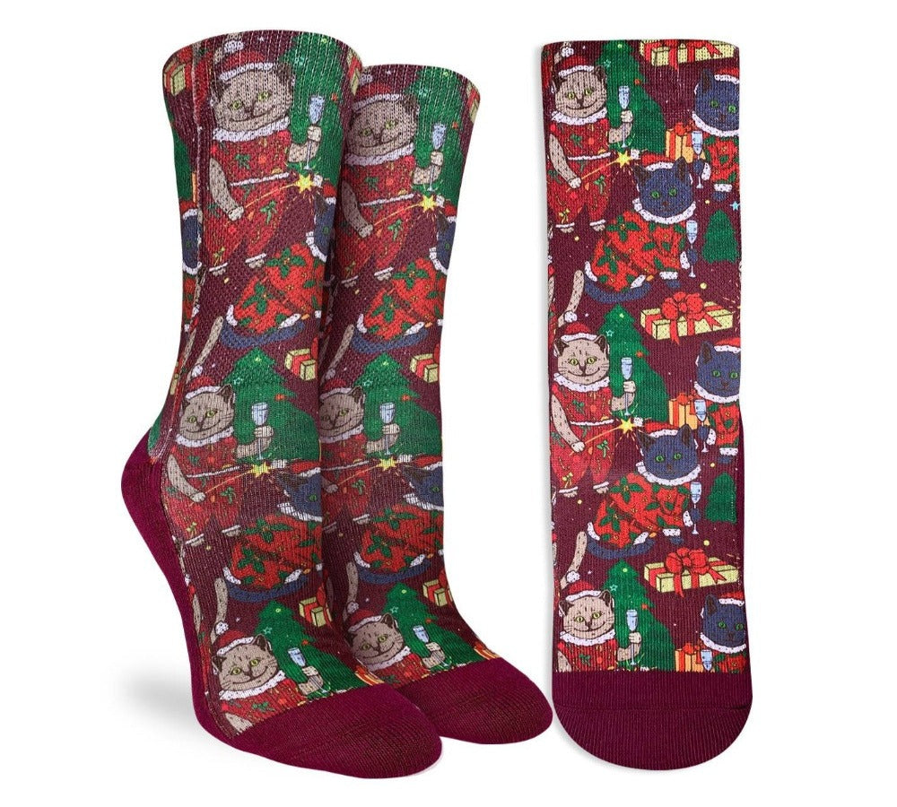 Burgundy socks showing grey and black cats in different santa-inspired outfits holding christmas presents with christmas trees