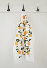 White kitchen green towen with pattern of oranges with green stems on black kitchen towel hooks 