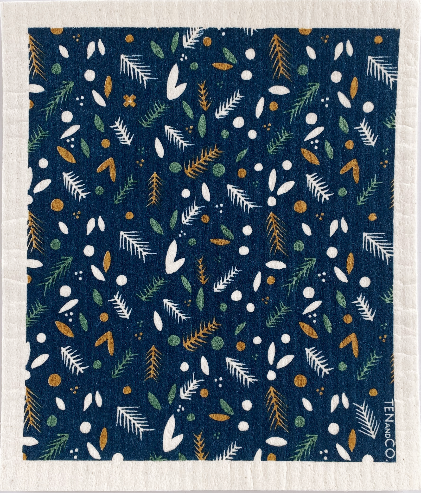 blue dishcloth with green, yellow, and white pine needles and berries in a pattern covering the towel.