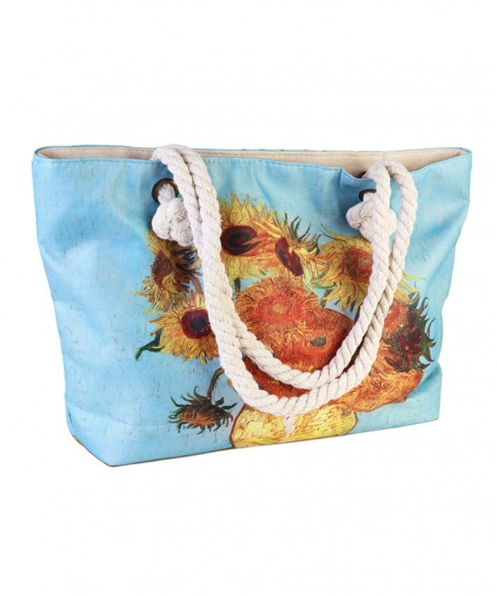 blue tote bag with white rope handles with an oil painting print of sunflowers in various different stages